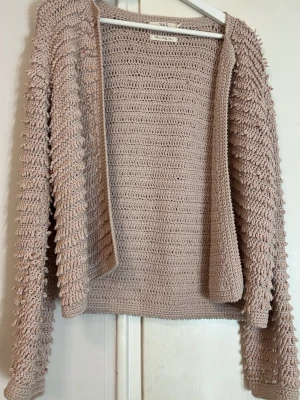 rosa kofta - Säljer en beige stickad kofta från 365 med långärmade ärmar och unik struktur med små öglor längs ärmarna. Koftan är öppen framtill och har en loose passform, perfekt att slänga på över en t-shirt eller linne. Supermysig och trendig för säsongen. Mer rosa i verkligen 