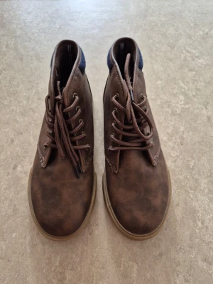 Kängor - Bruna kängor i skinnimitation (mockastil) med snörning och bekväm gummisula. Använda mycket lite, i fint skick.