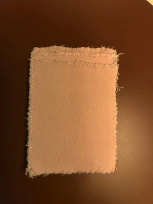 Rosa plånbok med sugproppar - Säljer en handgjord rosa plånbok i jeansmateriall med fransiga kanter. Ena sidan har sugproppar som gör att den kan fästas på släta ytor, som på till exempel en mobiltelefon. Perfekt för dig som vill ha något praktiskt och som är trött på att tappa bort betalkortet!