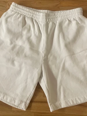 Shorts från Lacoste - Säljer ett par vita shorts från Lacoste i storlek M. De har en bred resår i midjan och är gjorda i mjuk bomull. Passformen är normal. Klassisk och enkel med snören 