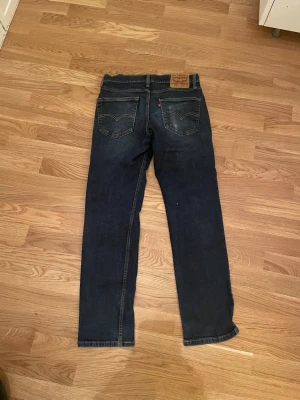 Levi's 514 mörkblå jeans W30 L30 - Säljer ett par Levi's 514 jeans i mörkblå tvätt med klassisk femficksdesign och raka ben. Jeansen har tydliga kontrastsömmar och patch med Levi's-logga bak i midjan. Perfekt för dig som gillar tidlös stil och bekväma jeans.
