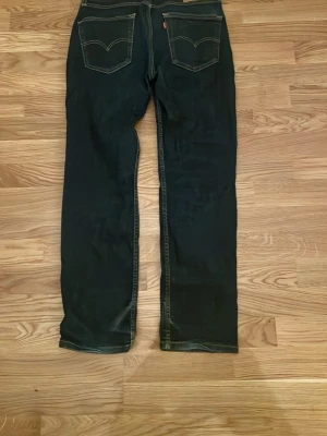 Levi's 514 svarta jeans W30 L30 - Svarta Levi's 514 jeans med klassisk femficksdesign och kontrastsömmar. Modellen har rak passform och normal midja, tillverkade i slitstarkt jeanstyg. Perfekta för dig som gillar stilrena och tidlösa jeans med snygg siluett.