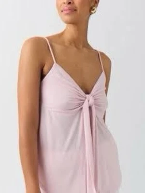 Ljusrosa linnetopp från Gina Tricot - Supersöt ljusrosa linnetopp från Gina Tricot med smala axelband och en stor knytrosett framtill. Toppen har en omlottliknande design och är tillverkad i mjuk bomull. Perfekt för varma dagar och enkel att styla med jeans eller kjol.