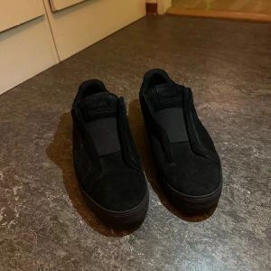 Svarta sneakers från Axel Arigato - Snygga svarta sneakers från Axel Arigato i mocka. Låg modell med platt sula och rund tå. Perfekt för dig som gillar minimalistisk och stilren design. Jag kan skicka dem inom kort tid!