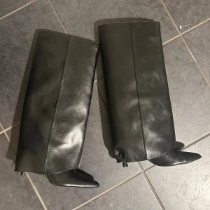 Svarta fold over stövlar med spetsig tå - Säljer ett par svarta höga fold over stövlar från Zara i slätt skinnimitation. Modellen har en bred och rak siluett med spetsig tå och klack. De behöver tyvärr klackas om för av det låga priset. 