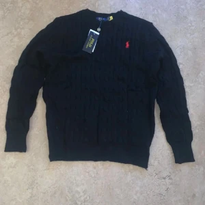 Svart stickad tröja Polo Ralph Lauren - Svart kabelstickad tröja från Polo Ralph Lauren, säljer den pga att den är för liten för mig ( är 190 )  förpackning, och alla lappar är kvar. Snygg tröja till vintern!