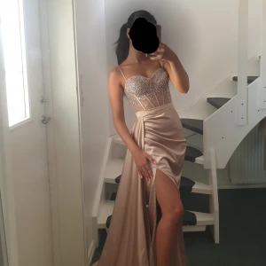 Balklänning, lyxig lång klänning. Pärlor - Lyxig balklänning från butik köpt 4500kr. Campangrosa pärlor stenar. Exlusive. Perfekt för bal, bröllop eller lyxigare evenemang. Är inte kemtvättad, därav pris! Så är smuttsig nertill som går att tvättas. Skräddaren har även klippt innertygdt för att klänningen ska lägga sig fint på marken. Tyg har även lossnat lite vid dragkedja som ses på bild, går att limma. 