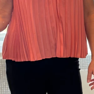 Plisserat, korallfärgat linne Express - Superfint plisserat festlinne från Express i en snygg korallton. Linnet har tunna axelband och v-ringning. Perfekt för dig som gillar en luftig och trendig look.