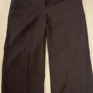 Svarta kostymbyxor från bikbok  - Snygga svarta kostymbyxor från 3H i klassisk rak modell. Byxorna har en midwaist passform och är tillverkade i ett slätt bomullsmaterial. Perfekta för en stilren look och passar dig som gillar enkel och clean stil.