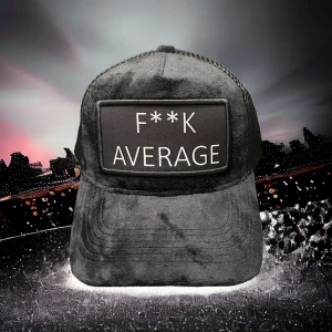 Svart keps med F**K AVERAGE-tryck - Svart keps i syntetmaterial med mjuk, nästan plyschliknande yta. Framtill sitter en stor patch med texten 'F**K AVERAGE' i vitt. Kepsen har klassisk böjd skärm och mesh baktill för extra ventilation. Perfekt statement-piece för dig som vill sticka ut.