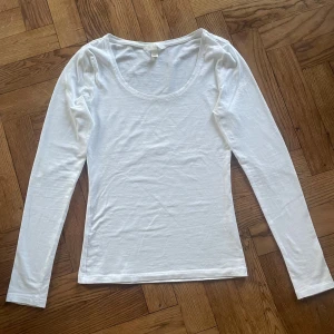 Vit långärmad topp från H&M XS - Säljer en enkel och stilren vit långärmad topp från H&M i storlek XS. Toppen har rundad halsringning och är gjord i mjuk bomull som känns skön mot huden. Perfekt att ha som basplagg och lätt att matcha med olika outfits.