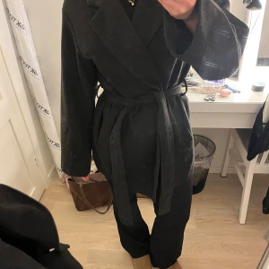 Mörkgrå kappa med bälte från 157 - Säljer denna otroliga kappa från lager 157. Säljer då jag önskar att ha en längre kappa. Den är använd en gång, så den är i ett ”nytt” skick! Nypris 400
