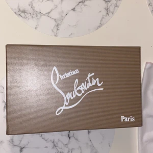 Christian Louboutin svarta sneakers - Säljer ett par svarta sneakers från Christian Louboutin i mocka med klassisk röd sula och diskret logga på sidan. Skorna har snörning och en stilren, rund tå. Kommer i originalkartong och dustbag. Perfekta för dig som vill ha en lyxig och clean look.