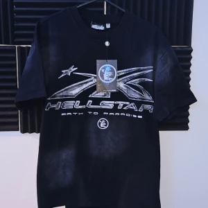 Hellstar t-shirt - Svart t-shirt från Hellstar med tryck i silver på både fram- och baksidan. T-shirten har rund hals och korta ärmar, tillverkad i mjuk bomull. (Tagg osv finns, helt oanvänt)