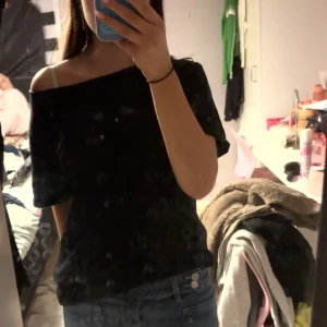 Svart offshoulder topp - Säljer en svart offshoulder topp med kort ärm. Toppen har en avslappnad passform och är perfekt för dig som gillar en enkel men snygg stil. Passar till både jeans och kjol för en cool look.