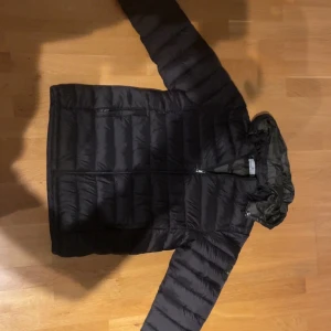 Svart pufferjacka från Stone Island - Pris kan diskuteras!Säljer en svart pufferjacka från Stone Island med ikonisk patch på ärmen. Jackan har huva, dragkedja framtill och quiltad design som ger en schysst look. Perfekt för kalla dagar och riktigt snygg till jeans eller cargo. Jackan är i medium och har en clean, modern vibe.