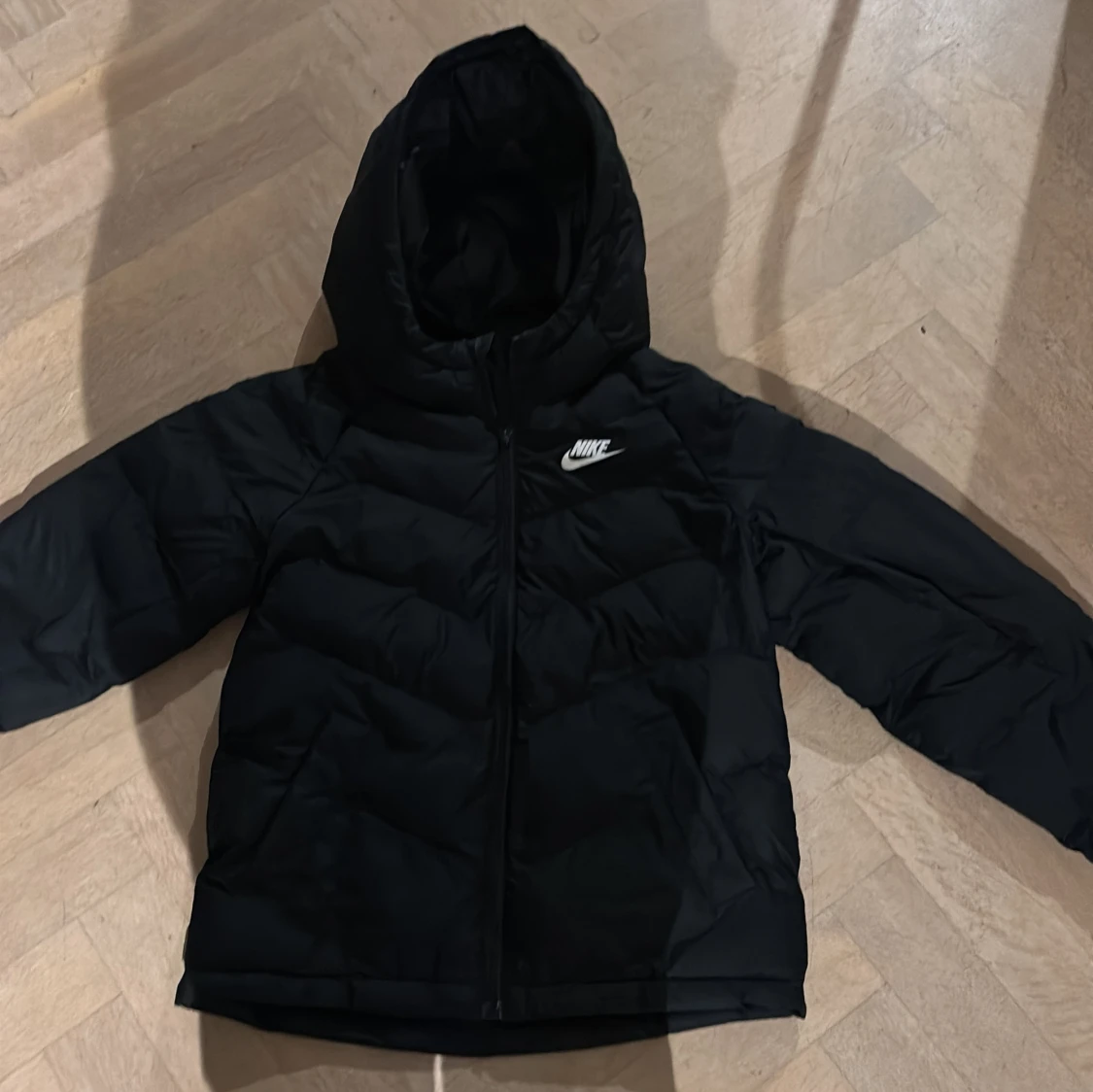 Svart pufferjacka från Nike med huva