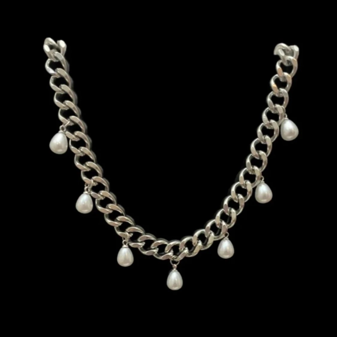 Silvrigt halsband med droppformade pärlor.