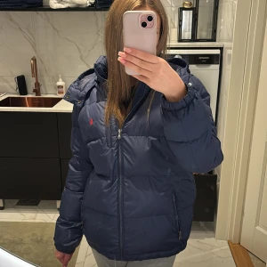 Mörkblå pufferjacka från Ralph lauren - Säljer min mörkblåa vinter jacka från ralph lauren, köpt förra året på kidsbrandstore så använd en vinter ungefär jackan är i storlek XL vilket motsvarar 163-174 men passar mig som har strolek S vanligtvis 