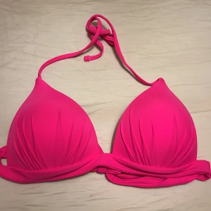 Rosa bikiniöverdel med knytband - Snygg trekantsbikini i starkt rosa med breda knytband i ryggen och nacken. Bikinin är oanvänd har lätt vadderade kupor och är tillverkad i ett mjukt, stretchigt material som sitter skönt. Perfekt för strandhäng och poolparty!