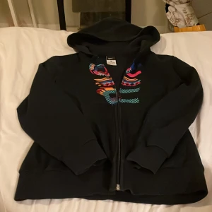 Snygg Nike hoodie med dragkedja  - Fin svart med tryck fram från Nike.Knappt använd alls.Storlek 150-160.