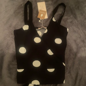 Prickig topp! - Prickig oanvänd omlottopp med lappen kvar från Anna Field! Toppen har knytning som man kan välja om man vill ha fram eller bak, storlek XS!