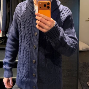 Marinblå stickad kofta från Burton - Marinblå stickad kofta från Burton med grovt kabelmönster och stora knappar framtill. Storlek L