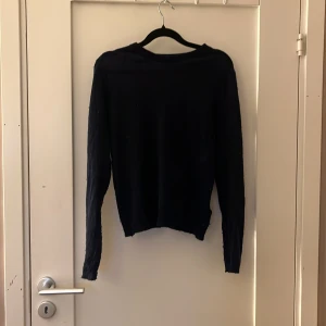 Mörkblå stickad tröja från Zara - En enkel och stilren mörkblå stickad tröja från Zara. Tröjan har rund halsringning och långa ärmar, perfekt för lager-på-lager under kyligare dagar. Passformen är normal och materialet känns mjukt mot huden. Den är lite nopprig men kan dra med min knoppermaskin innan jag skickar den