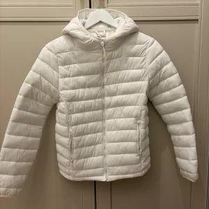 Vit pufferjacka från Pull&Bear - Säljer en fräsch vit pufferjacka från Pull&Bear i storlek S. Jackan har huva, två sidofickor med dragkedja och quiltad design. 