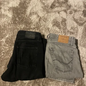 Jack & Jones svarta och grå jeans - Två par jeans från Jack & Jones, ett par i svart och ett par i ljusgrått. Modellen är Loose/Chris vilket ger en avslappnad och trendig passform. Säljer för billigt pris då jag vill bli av med dom och säljer dom i samma ”paket”. Du måste alltså köpa båda och kan inte bara köpa en av dom. Hör av dig om du har någon fråga! 