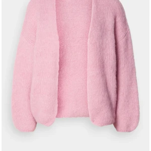 Ljusrosa stickad kofta - Mysig ljusrosa stickad kofta med lång ärm och öppen front. Koftan har en avslappnad passform och är perfekt att slänga på sig när det är lite kyligt. Den fluffiga känslan gör den extra skön och trendig. Lindex lappen är bortklippt!!