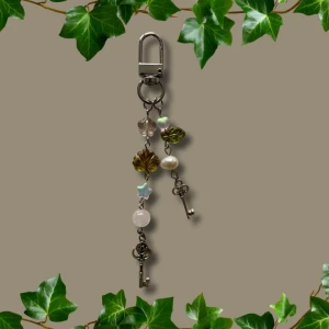 Keychain  - Keychain med rosenkvarts, tjeckiska glaspärlor, en upcycled sötvattenpärla & charms i form av nycklar. Går att sätta på väska exempelvis, väldigt Fairycore :)🌿✨