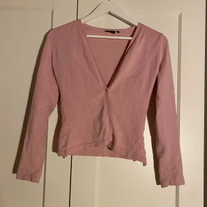 Rosa kofta från InWear Essentials - Säljer en söt ljusrosa kofta från InWear Essentials i storlek S. Koftan långa ärmar och knäppning framtill. Har själv sytt in den i midjan så den sitter mot kroppen. Enkel och stilren design som funkar till många outfits.