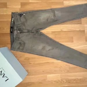 Replay grå jeans slim fit - Snygga grå jeans från Replay med klassisk femficksdesign och diskret logga vid fickan. Jeansen har en slim passform och raka ben, tillverkade i mjukt bomullsmaterial med lite stretch för extra komfort. Perfekta för dig som gillar stilrena och enkla jeans. Modellen är anbass 30-30