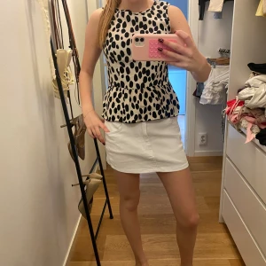 Vit mini jeanskjol - Snygg vit kortkjol med klassisk jeanslook och praktiska fickor både fram och bak. Kjolen har en rak passform. Perfekt för dig som gillar en clean och fräsch stil.