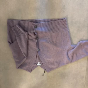 Ljuslila kofta från H&M XXL - Säljer en ljuslila kofta från H&M i storlek XXL. Koftan har ribbade muddar, dekorativa knappar framtill och är långärmad. Den är använd och därför lite nopprig men i övrigt fint skick.