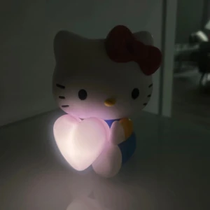 Hello Kitty nattlampa - Söt Hello Kitty nattlampa med hjärta som lyser mjukt. Perfekt för barnrum eller som dekorativ belysning. Lampan är i gott skick utan synliga skador eller slitage.