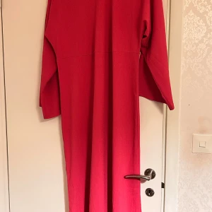 Chockrosa långklänning från Trendyol - Säljer en chockrosa ribbad Maxiklänning i Jersey med pingvinärmar  från Trendyol. Klänningen är tillverkad i ett strukturerat, lätt skrynkligt tyg som ger en cool känsla. Perfekt för dig som gillar enkel men snygg stil.