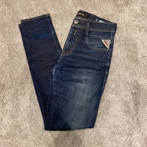 Replay anbass jeans - Säljer ett par snygga mörkblå jeans från Replay med klassisk femficksdesign, gul kontrastsöm och Replay-logga på fickan. Jeansen har slim passform och är tillverkade i stretchigt denim för en bekväm känsla. Perfekta för dig som gillar en smal siluett.