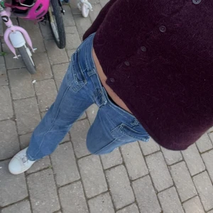 Blå lågmidjade jeans  - Säljer ett par blå  jeans med låg midja från nelly, jeansen har coola fickdetaljer fram, nåra få slitningar finns nertill