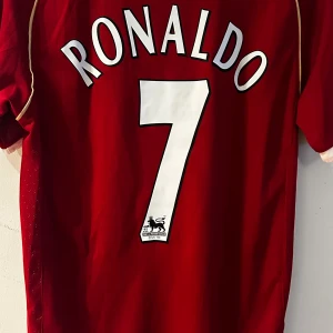 Manchester United Ronaldo 7 Nike tröja - Klassisk Manchester United fotbollströja med Ronaldo 7 på ryggen. Röd med vita detaljer, klubbmärke och AIG-logga framtill. Tillverkad i 100% polyester, officiell Premier League-licens. Perfekt för fans som vill sticka ut på match eller i vardagen.