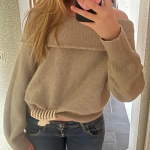 Beige offshoulder stickad tröja - Supermysig beige stickad tröja med offshoulder-modell och bred ribbad kant upptill. Tröjan har en loose passform och långa ärmar. 💖