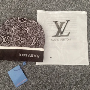 Svart stickad mössa med logga framtill - Fin mössa i bra skick. Använd ett fåtal gånger. Passar både vardag och utomhusbruk. 