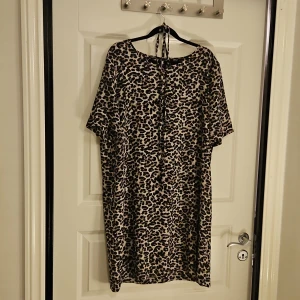 Leopardmönstrad kortklänning från ONLY - Snygg kortklänning från ONLY med leopardmönster i beige och svart. Klänningen har rund hals, korta ärmar. Knytband i midjan om man vill. Avslappnad passform 