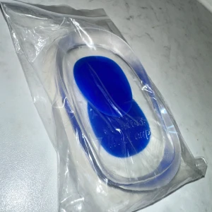 Blåa gel-hälkuddar för skor - Säljer ett par genomskinliga och blåa gel-hälkuddar som ger extra komfort och stöd i dina skor. Perfekta att lägga i sneakers eller andra skor för att dämpa stegen och minska belastningen på hälarna. Gjorda i mjukt syntetmaterial.Genom att använda ett mjukt och stötdämpande hälinlägg avlastar du hälsporren direkt. 