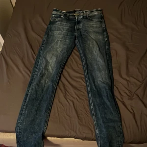 Jack & Jones Tapered Mike jeans blå 28/32 - Snygga blå jeans från Jack & Jones, modell Tapered Mike. Jeansen har en klassisk femficksdesign, gul kontrastsöm och en tvättad look med slitningar. Passformen är tapered vilket ger en modern siluett. Perfekta för dig som gillar stilrena och bekväma jeans. Jeansen är i bra skick och har inga skador. Storlek: Längd - 32 Bredd - 28. Säljes på grund av att dom är för små. Nypris: 899kr. Hör av dig vid fler frågor eller bilder!