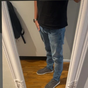 Replay ljusblå jeans herr - Säljer ett par ljusblå jeans från Replay med klassisk femficksdesign och snygga detaljer på bakfickan. Jeansen har normal passform och raka ben, tillverkade i mjukt denimtyg. Perfekta för dig som gillar stilrena och bekväma jeans.