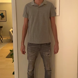 Grå pikétröja från 157, storlek M - Säljer en stilren grå pikétröja från 157 i storlek M. Tröjan har klassisk krage, korta ärmar och knäppning framtill. Perfekt för dig som gillar en enkel och clean look. Tillverkad i mjuk bomull för skön känsla hela dagen.