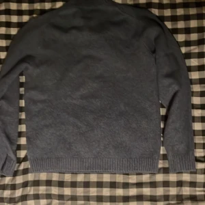 Blå stickad tröja från Uniqlo - Mysig blå stickad tröja från Uniqlo i storlek M. Tröjan har en enkel design med ribbade muddar vid ärmslut och nederkant. Perfekt för att hålla värmen under kyliga dagar och passar dig som gillar stilrena plagg. Använd en gång 10/10skick.