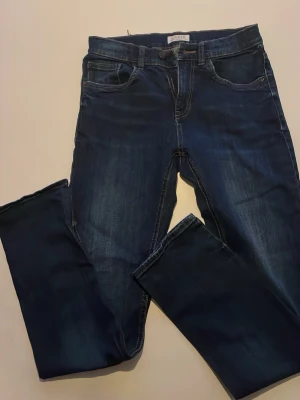 Mörkblå jeans från Lindex - Snygga mörkblå jeans från Lindex med klassisk femficksmodell och raka ben. Jeansen har kontrastsömmar och en lätt tvättad look framtill. Perfekta till vardags och passar till det mesta. Materialet är slitstarkt jeans med lite stretch.